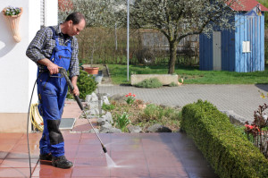 man pressure washing patio